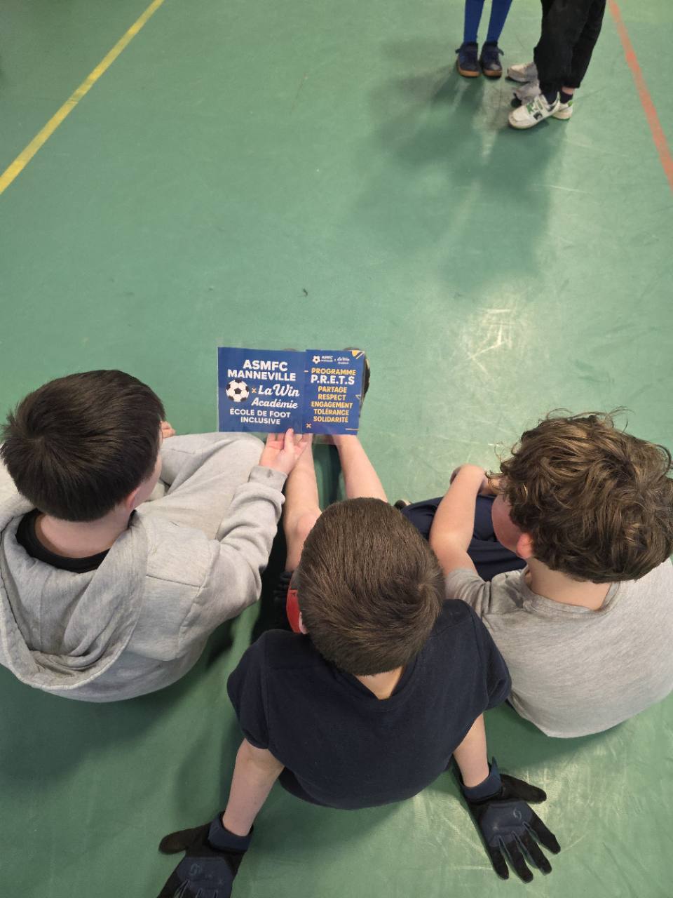 Trois jeunes assis consultent un support du programme éducatif